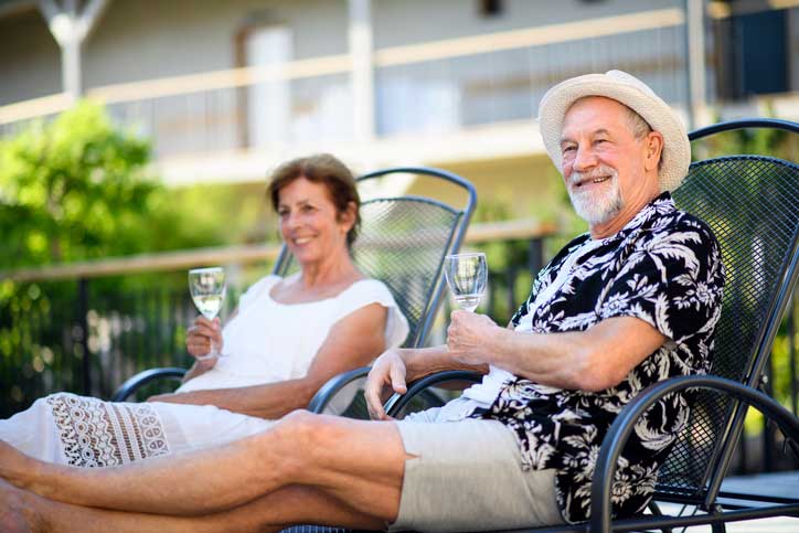 senior couple enjoying a glass of wine by the pool