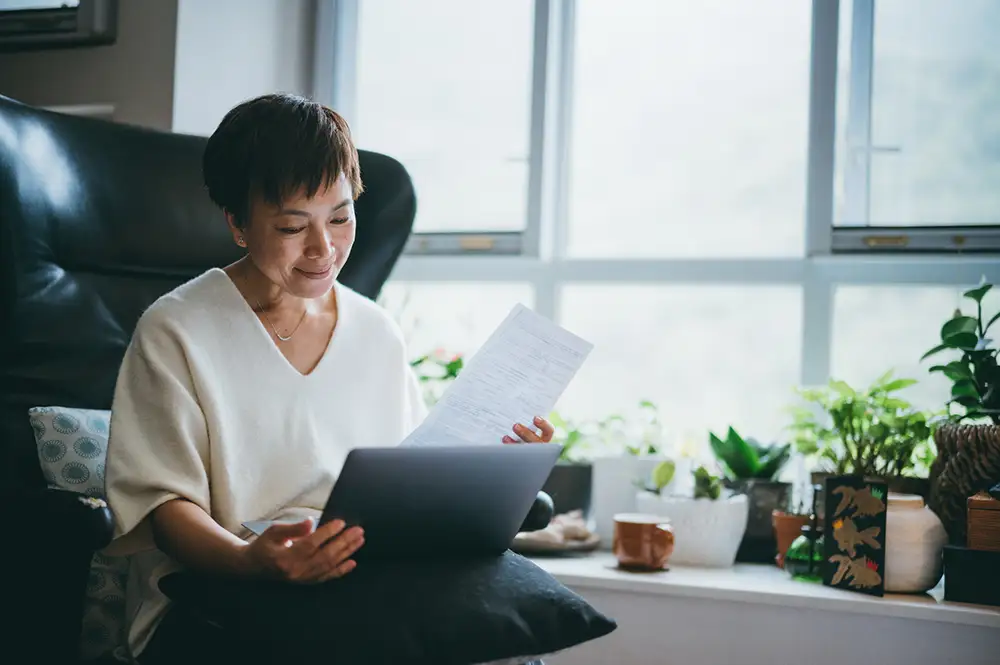 An elderly woman sitting in her home at Amavida reading about the five emotional stages of retirement in Fort Myers, Florida.