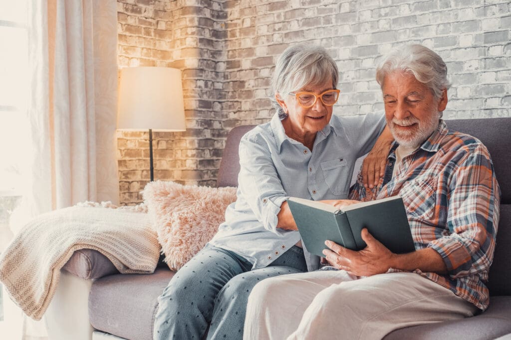 senior couple reading book on couch